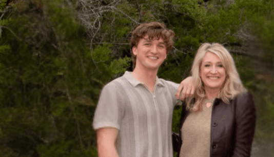 A photo of Luke Beasley smiling with his hand on his mom, Leslie's, shoulder